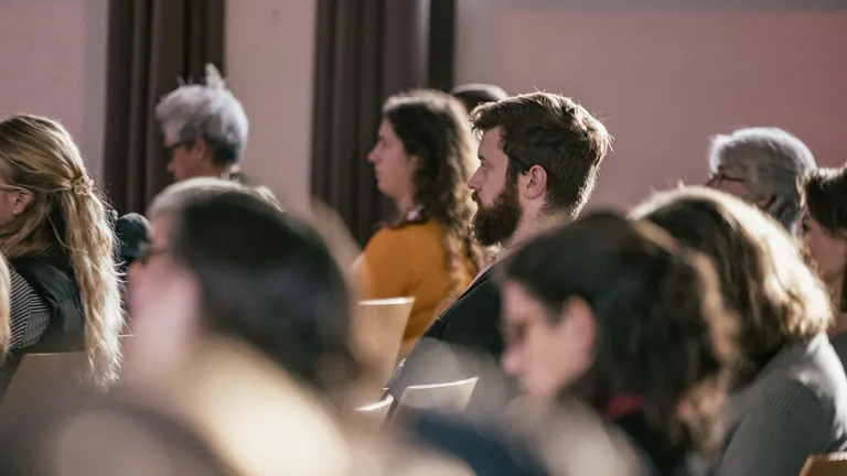 People are sitting in a plenary session; except for one man, all the other people are blurred and cannot be clearly recognised.